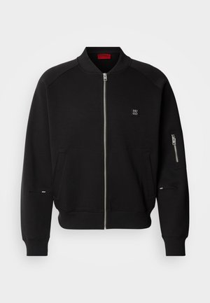 Black zip-up bomber jacket with ribbed collar, side pockets, and zip pocket on the sleeve. Features a logo patch on the chest and smooth texture.