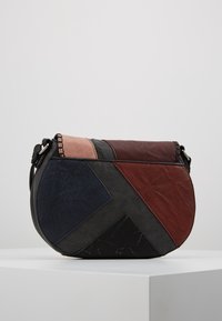 Kabelka přes tělo s geometrickým designem, která obsahuje části z černé, modré, vínové a růžové kůže. Má hladký povrch.