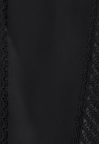 Svart tyg med två vertikala paneler av blommig spetskant som har scallopade kanter på varje sida.