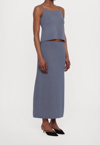 Gray knitted crop top and matching long skirt, made from soft fabric with a smooth texture. Simple design with thin straps.