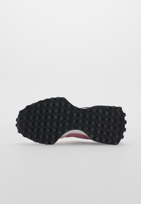 Semelle extérieure en caoutchouc noir avec des points de traction ronds, se transformant en une semelle intermédiaire incurvée. Tige rose clair en textile avec des accents texturés subtils.