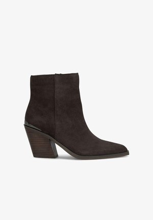 Botín de ante en marrón oscuro con punta afilada y tacón apilado en ángulo. Presenta una superficie suave y un detalle mínimo.