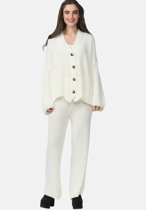 Hvid strikket cardigan med store knapper, parret med matchende ribbede bukser. Har en afslappet pasform og tekstureret stof.