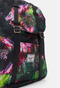 Monivärinen reppu, jossa musta pohja, kirkkaat abstraktit kuviot, nahkaiset yksityiskohdat ja metallisoljet. Mukana etutasku.