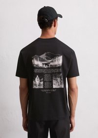 Schwarzes T-Shirt mit einem detaillierten monochromen Grafikdesign auf dem Rücken, einschließlich Berglandschaften und Text, mit kurzen Ärmeln und Rundhalsausschnitt.
