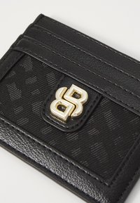 Portafoglio nero realizzato in materiale sintetico testurizzato con rifiniture lisce, dotato di multiple fessure e un accento del logo in tonalità oro.