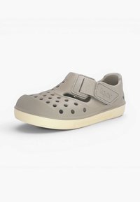 Sabot en caoutchouc gris clair avec des trous de ventilation, une semelle beige et une bride réglable étiquetée "igor" sur le côté.