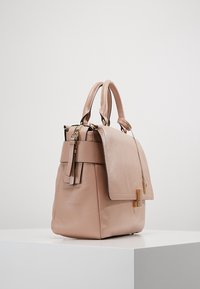 Mjuk rosa läderhandväska med dubbla överhandtag, en vikflik och detaljer i guldton. Har en texturerad yta och en fransdetalj.