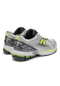 Γκρι και μαύρα αθλητικά παπούτσια με επάνω μέρος από δίχ τυ, νέον κίτρινα στοιχεία, επένδυση στη φτέρνα και υφή στις σόλες σχεδιασμένες για υποστήριξη και άνεση.