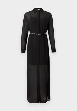 Robe chemise noire fluide en tissu transparent, manches longues, col, et ceinture en chaîne argentée. Présente une patte de boutonnage à l'avant et des fentes latérales.