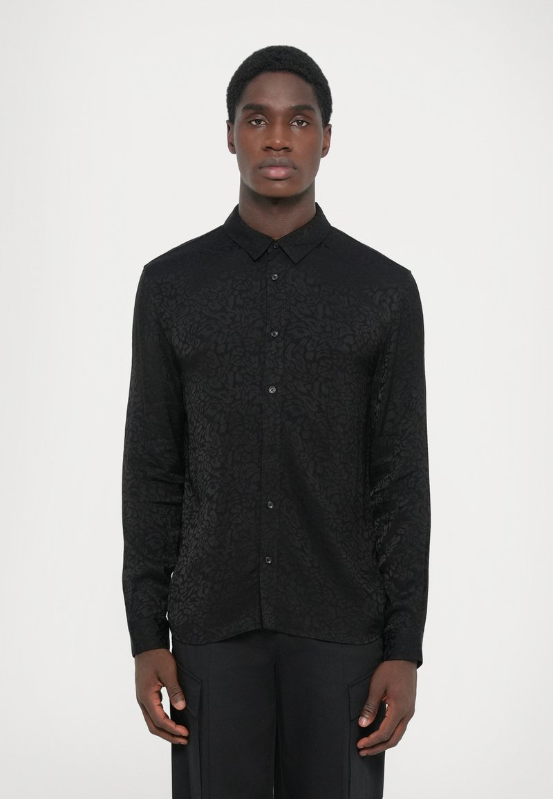 Black button-up shirt with an embossed floral pattern, long sleeves, and a classic collar. Made of textured fabric, it features a tailored fit.