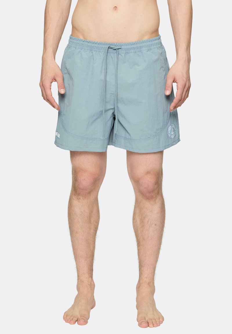 Svetlomodré plavky vyrobené z ľahkého materiálu, s elastickým pásom so šnúrkou a bočnými vreckami. Obsahuje akcent loga.