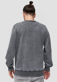 Felpa grigia con maniche lunghe, polsini a costine e scollo rotondo. Presenta una texture morbida e un design pulito sulla schiena senza loghi visibili.