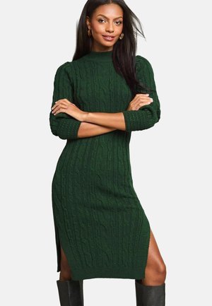 Robe tricotée verte avec un motif de câbles texturé, col haut, manches trois-quarts et fentes sur les côtés. Fabriquée en matériau doux et chaud.