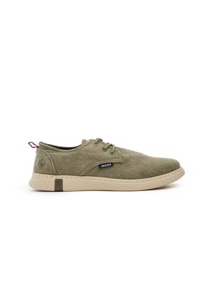 Zapatos de tela verde oliva con suela de goma beige, puntera redonda y diseño con cordones. Presentan una etiqueta negra con "INSIDE" y una lengüeta.