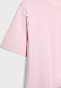 Světle růžové bavlněné tričko s krátkými rukávy a kulatým výstřihem, zobrazené z horní levé strany na bílém pozadí.