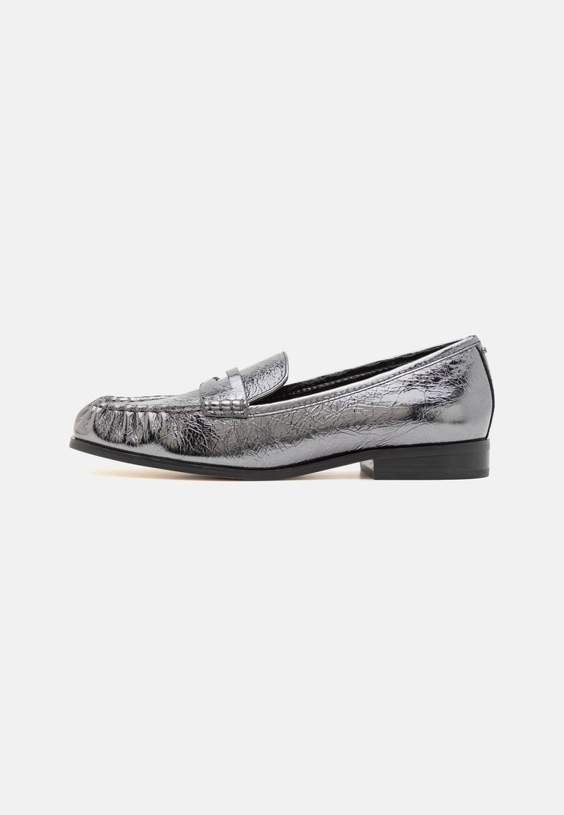 Mocassin en cuir argenté métallique avec un petit talon noir et des détails cousus sur l’avant, présenté de côté sur fond blanc.