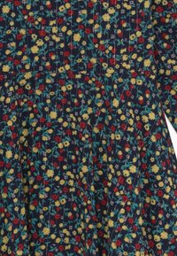Kwiatowa sukienka z granatowym tłem w czerwone, żółte i zielone kwiaty. Tkanina ma teksturowany wzór z pionowymi detalami szycia.