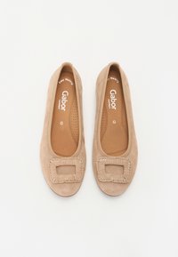 Ballerine in suede beige con un dettaglio decorativo quadrato sulla punta. Presentano una soletta imbottita e un design perforato per la traspirabilità.