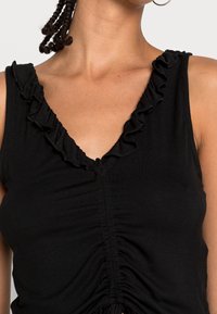 Top senza maniche nero con scollatura a V, rifinito con dettagli arricciati e pieghe sul davanti, realizzato in tessuto morbido e elasticizzato.