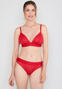 Red lingerie set featuring a wire-free bralette with a wave pattern and adjustable straps, paired with matching sheer bikini panties.