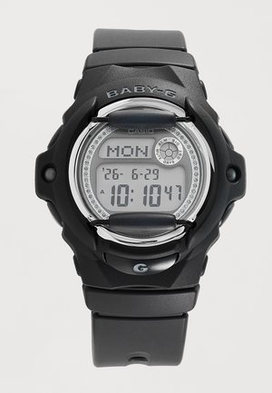 Montre numérique noire Casio Baby-G affichant la date du lundi et l’heure 10:10:47 avec des protections sur le cadran et un bracelet en caoutchouc.