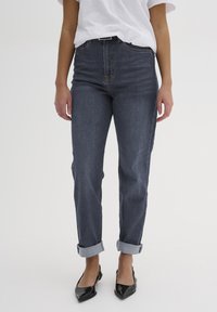 Jeans in denim blu scuro con vita alta, gamba dritta e orli arrotolati. Presentano tasche anteriori e posteriori e dettagli di cucitura discreti.