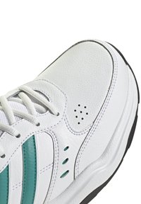 Vit sportskor med övre i texturerat läder, turkosa ränder, snörningsdesign och perforerade detaljer på sidan. Svart gummisula.