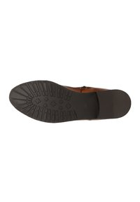 Bottine en cuir marron avec une semelle en caoutchouc texturée, présentant un motif en zigzag pour une meilleure adhérence et un côté lisse et fini avec un détail de fermeture éclair.