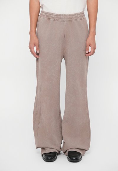 Pantaloni cu talie înaltă și picioare largi dintr-un material bej estompat. Prezintă un brâu elastic și șeve laterale, având o textură netedă.
