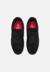 Black suede sneakers with a textured finish, featuring lace closures, padded collars, and red insoles with branding details.