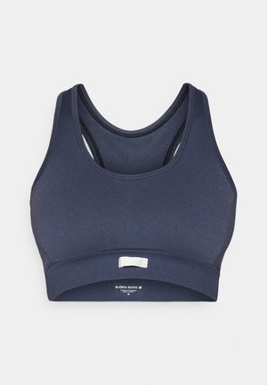 Dunkelblauer nahtloser Sport-BH mit Racerback-Design und elastischem Unterband, mit einem kleinen weißen Etikett auf der Vorderseite.