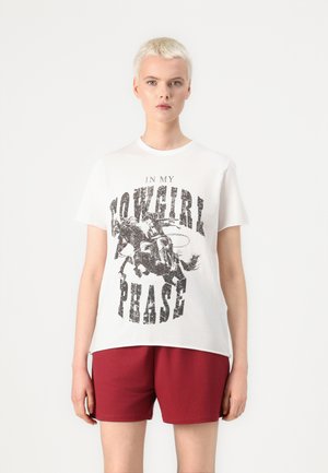 T-shirt en coton blanc avec un imprimé graphique d'un cheval bucking et le texte "DANS MA PHASE DE COWGIRL" en lettres noires grasses et usées.