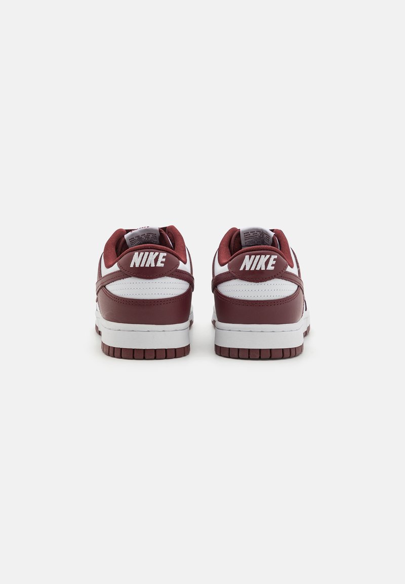 Zapatillas Nike, de cuero burdeos con acentos blancos, punta redondeada, cuello acolchado, suela texturizada, con el logo "NIKE" en el talón.