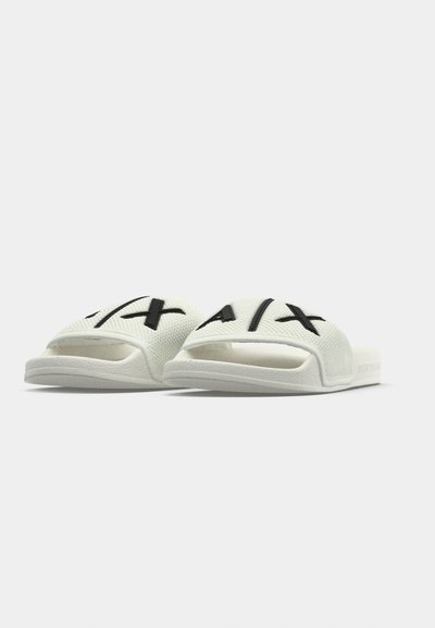 Sandales blanches à enfiler avec une tige texturée, ornées d'accents de logo noirs. Le design comprend un bout ouvert et une semelle durable.