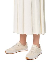 Sneaker beige con parte superiore in suede e mesh, design con lacci e suola in gomma. Presenta dettagli dorati sulla linguetta e sul lato.