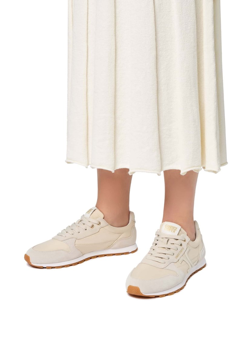 Sneaker beige con parte superiore in suede e mesh, design con lacci e suola in gomma. Presenta dettagli dorati sulla linguetta e sul lato.