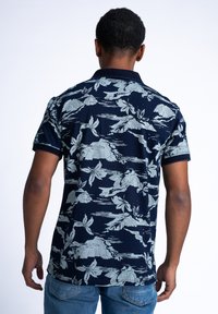 Námořnická polo košile s krátkým rukávem s světle šedým vzorem hor a květin. Látka je hladká s límečkem a zúženými rukávy.