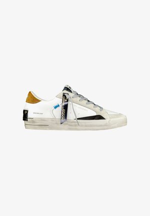 Sneaker in pelle bianca con lacci grigi, dettagli neri e un inserto in suede marrone sul tallone. Presenta una suola in gomma e un'etichetta con il marchio.