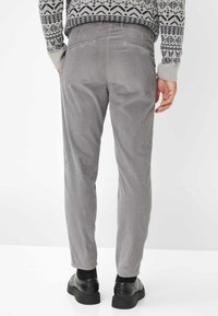 Pantaloni in corduroy grigi a vestibilità slim, con due tasche posteriori e un tessuto testurizzato, abbinati a scarpe nere.