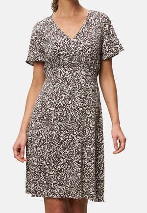 Mujer vistiendo un vestido marrón y blanco con estampado de hojas hasta la rodilla, con mangas cortas acampanadas y escote en V con tres botones.