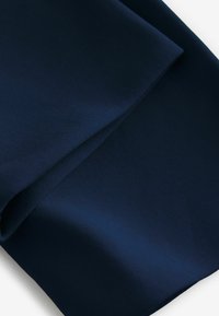 Tmavě modrá tkanina s hladkou strukturou, zdobená složenými vrstvami, které vytvářejí jemnou hloubku a pohyb. Žádné viditelné vzory ani designy.