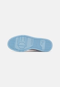 Suola di sneaker azzurro chiaro con grip testurizzato, motivi circolari e ondulati, logo in rilievo e linee di battistrada ben definite per una buona trazione.