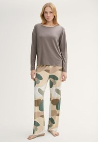 Grijze lange mouw top gecombineerd met beige pyjamabroek met grote groene en bruine organische vormen; zachte stof met een ontspannen pasvorm.