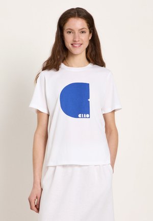 Young woman with long brown hair wearing a white t-shirt printed with a large blue semi-circle and the word "CIAO" in white letters.