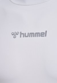 Vit sporttröja gjord av slät, elastisk tyg med en subtil bikakestruktur. Hummel-logotypen i ljusgrått.