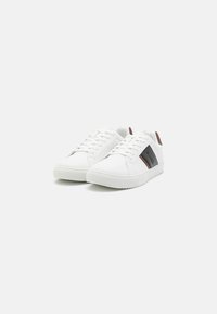 Weiße Sneaker mit glatter Oberfläche, seitlichen Akzenten in dunkelgrau und braun, flachen Schnürsenkeln und einer strukturierten Gummisohle.
