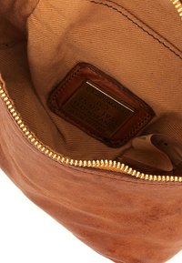 Interno di una borsa in pelle marrone con una cerniera dorata, caratterizzato da una fodera in tessuto beige e un'etichetta con testo impresso che dice "CAMPOMAGGI."