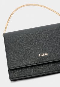 Clutch in ecopelle nera testurizzata con tracolla in oro. Dotato di chiusura a scatto e logo del marchio impresso. Design compatto ed elegante.