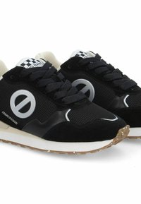 Des chaussures de sport noires avec une tige en mesh, des accents en daim, un grand logo circulaire, un motif en damier sur la languette et une semelle en caoutchouc texturé.